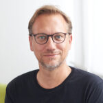 Carsten Mesecke von Rheinbaben steht vor einem weißen Hintergrund