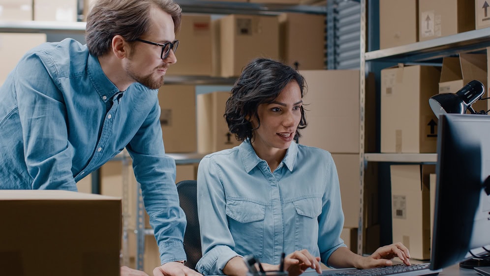 Female warehouse worker and colleague working in the warehouse with a computer.
