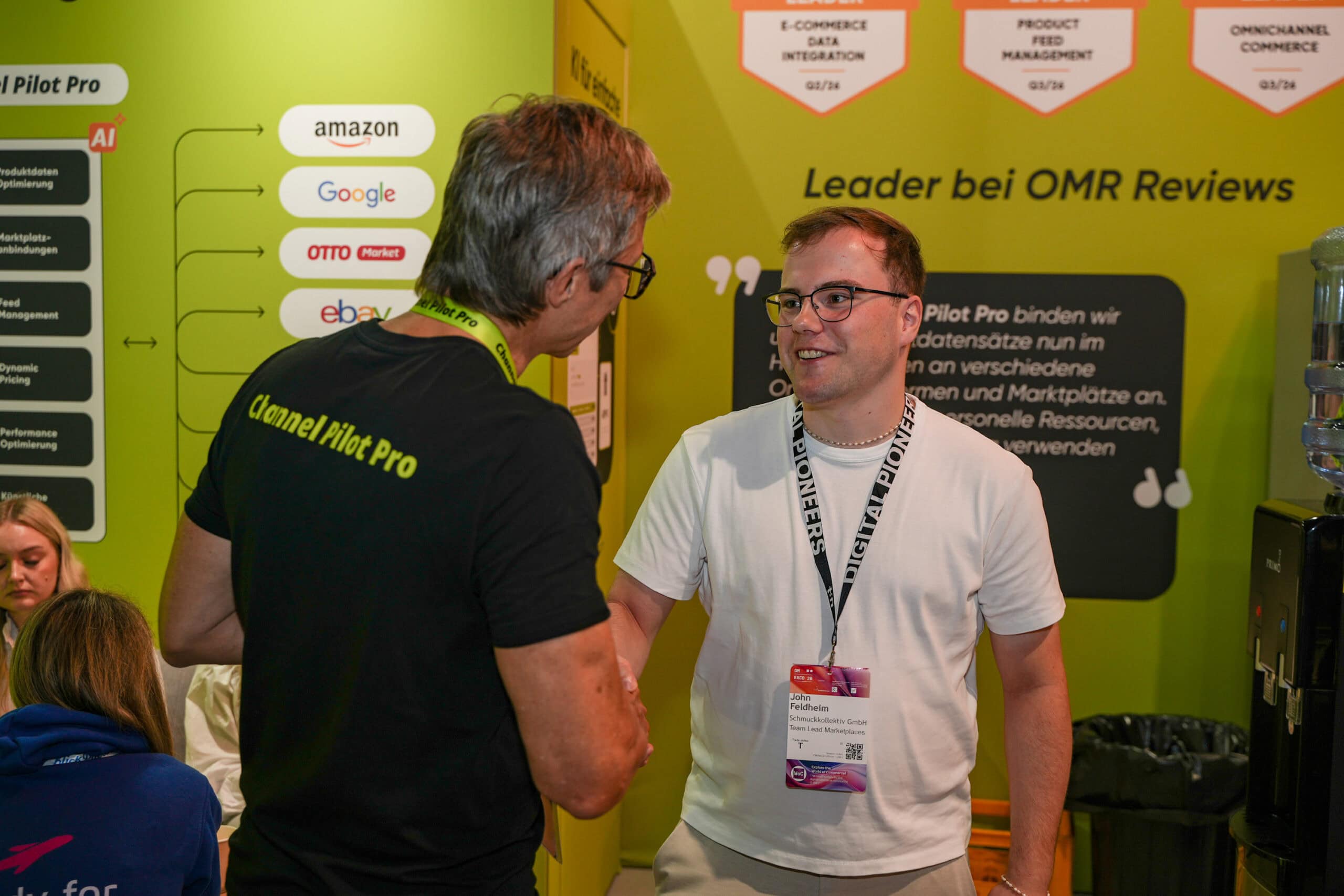 Zwei Männer im Gespräch auf einer Messe, hinter ihnen ein Stand von Channel Pilot Solutions.