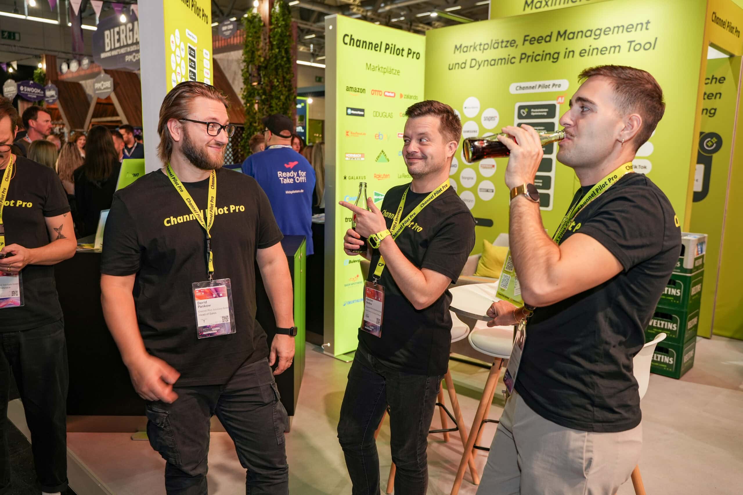 Drei Männer im Gespräch auf einer Messe mit Channel Pilot Solutions Stand.
